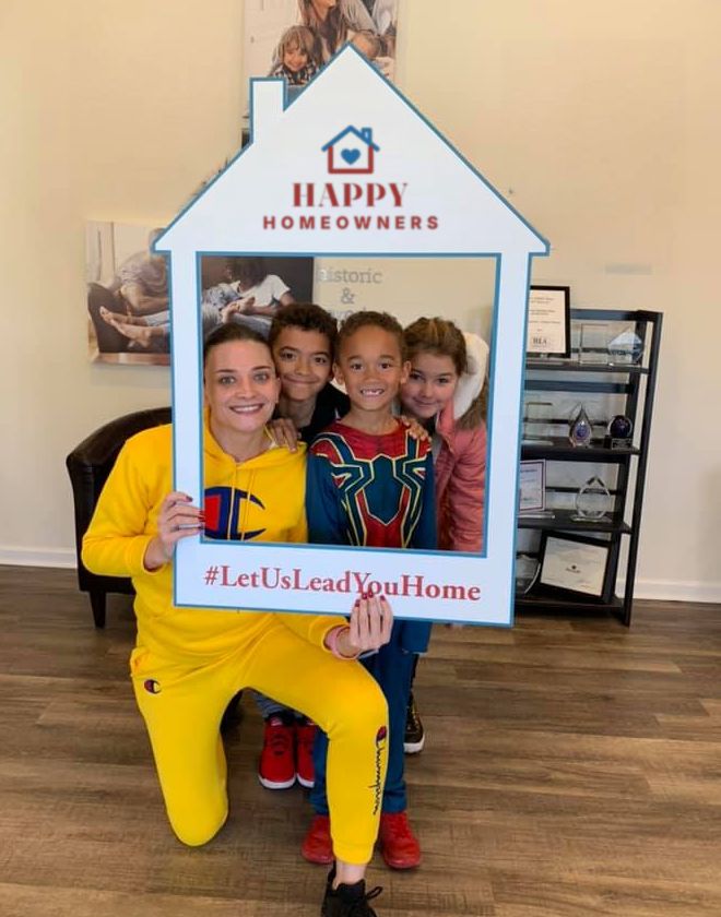 A mom and three kids smiling inside a house-shaped photo frame
