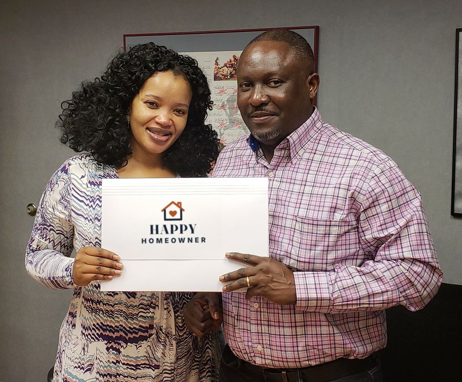 A smiling couple holding their closing folder