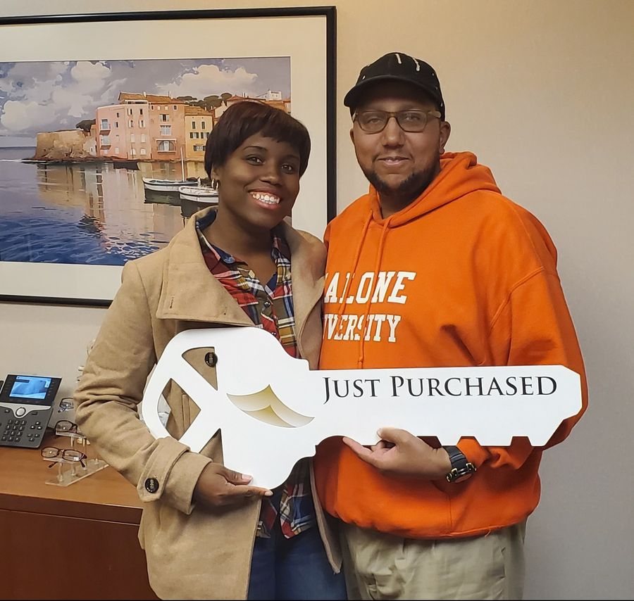 A couple holding a giant Just Purchased key