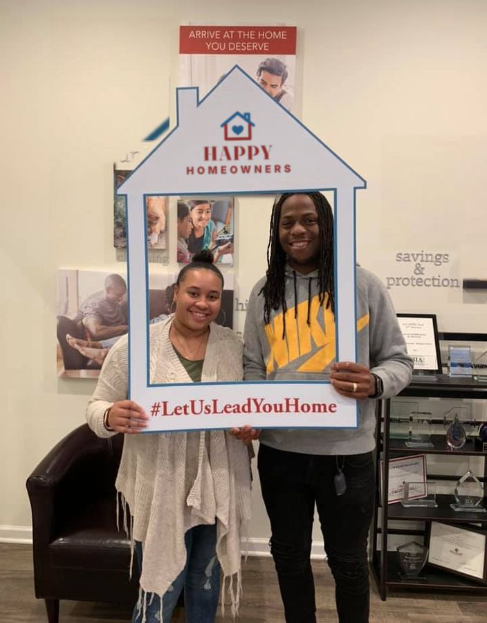A couple posing in a house-shaped photo frame