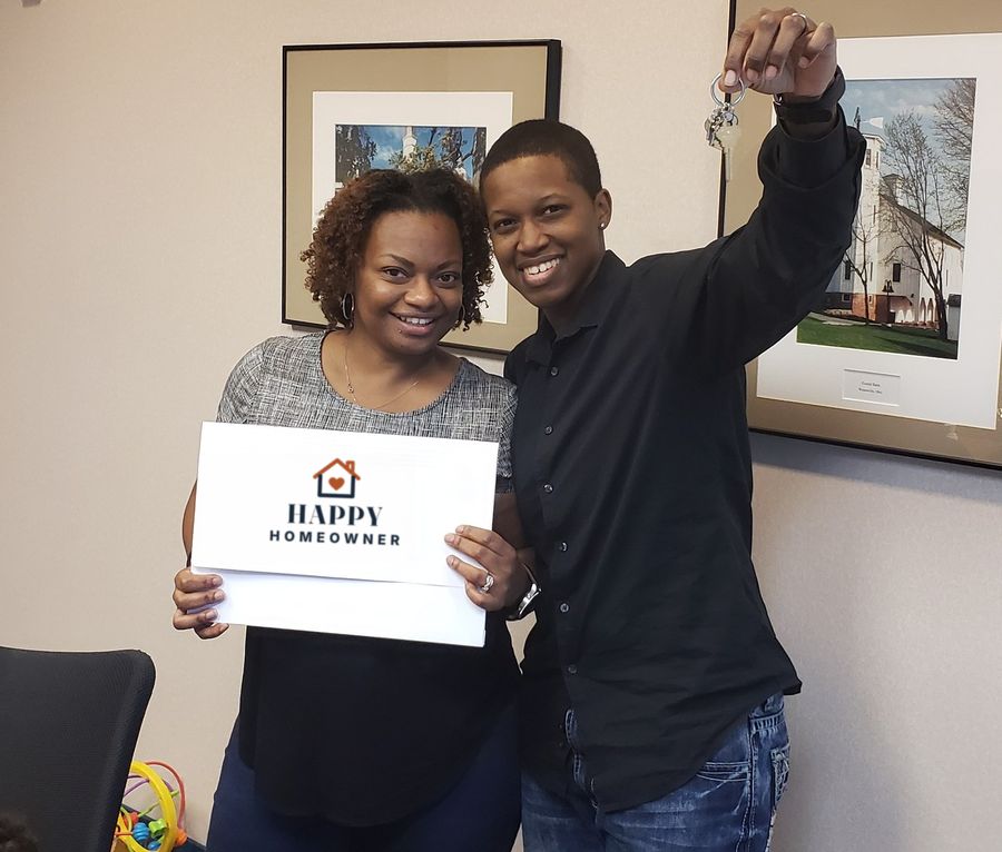 Two new homeowners holding up their keys