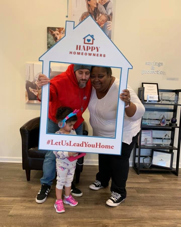 A family posing in a house-shaped photo frame